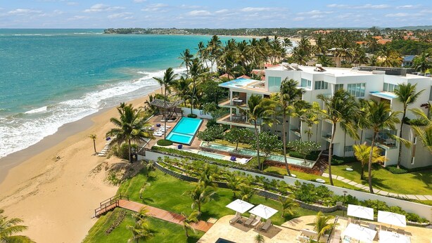 Ein Strandhotel mit Pool, Palmen und Meerblick.