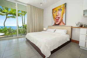 A hotel room with a bed, a painting, a coffee machine, and a view of the ocean. - Beachfront Luxury Studio • Ultravioleta Cabarete (Cabarete)
