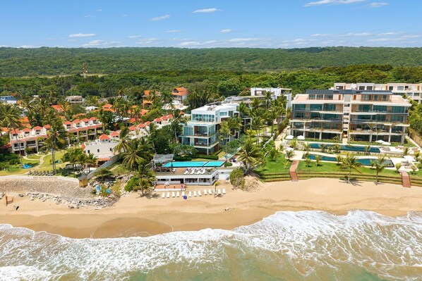 A coastal resort with beachfront villas, a pool area, and a beach with lounge chairs. - Beachfront Luxury Studio • Ultravioleta Cabarete (Cabarete)