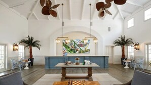 Une pièce spacieuse avec une table en bois, deux chaises, un mur d’accent bleu et un ventilateur de plafond.