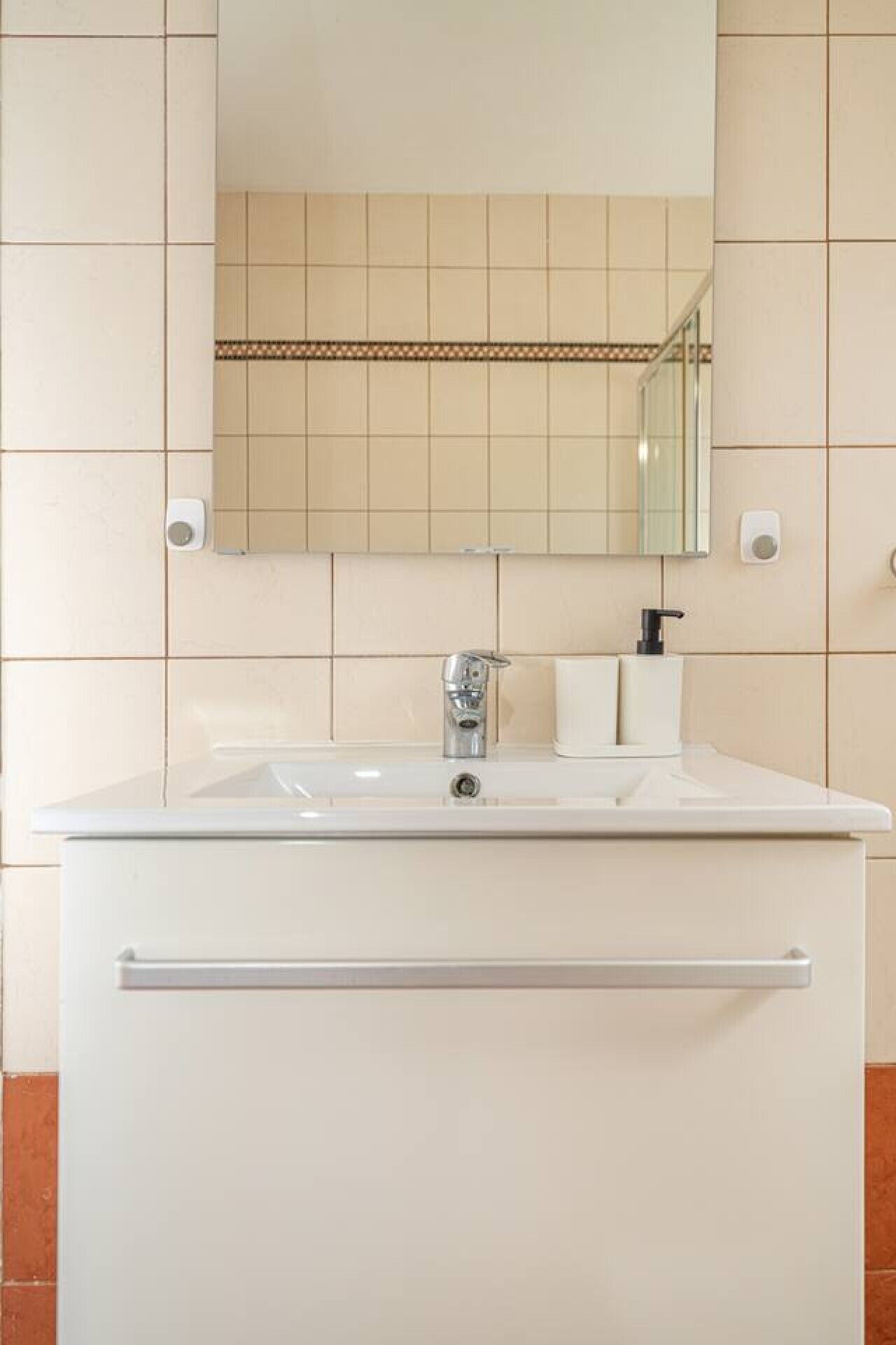 A bathroom with a white sink, a mirror, and a towel rack.