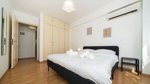 Ein Schlafzimmer mit einem Bett, Nachttischen, einem Kleiderschrank und einer Klimaanlage.