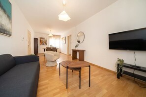Ett modernt vardagsrum med en soffa, ett matbord, en tv och en spegel.