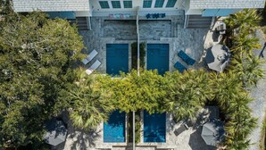 Vista aérea de un hotel con piscina central, rodeado de palmeras y zonas de descanso.