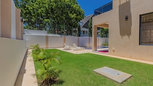A modern building with a well-maintained lawn, outdoor seating area, and a clear view of the surrounding trees. - 2 or 3 Bedroom - A&E Residence  (Kwale County)
