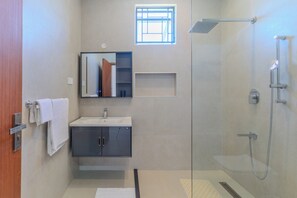 A modern bathroom with a glass shower enclosure, a sink with a mirror above it, and a towel rack. - 2 or 3 Bedroom - A&E Residence  (Kwale County)
