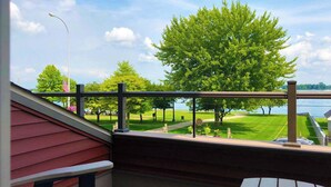 A balcony with a view of a grassy area and a body of water.