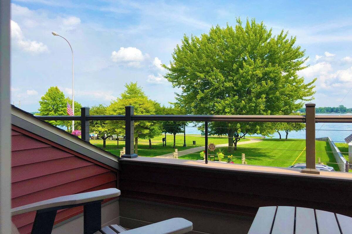 A balcony with a view of a grassy area and a body of water.