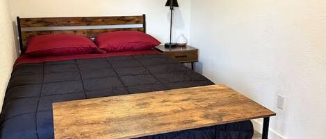 Ein Schlafzimmer mit einem Bett, einem Nachttisch aus Holz, zwei Lampen und zwei Bildern an der Wand.
