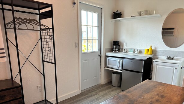 Una cocina compacta equipada con microondas, cafetera y lavamanos.