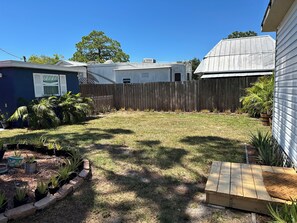 Ein Garten mit Holzzaun, Blumentöpfen und einer kleinen Holzhütte.