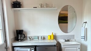 Una kitchenette compacta con microondas, refrigerador Galanz, cafetera y un lavamanos pequeño.