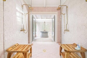 Een badkamer met honingraatmozaïek, houten banken en een bad.
