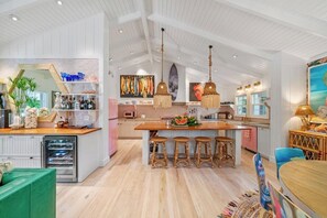 Una cocina amplia con una isla central, taburetes de bar y un comedor con mesa y sillas.