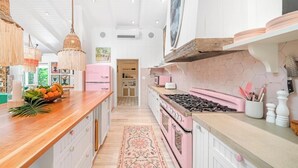 Ett kök med en köksö i mitten, en rosa spis och en hängande lampa.