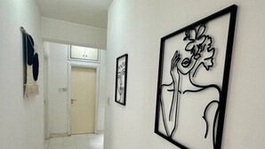 A hallway with framed abstract art, a door, and a wall-mounted towel rack. - 2 bedrooms flat near center (Egkomi)