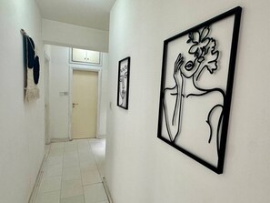 Ein Flur mit gerahmten abstrakten Kunstwerken, einer Tür und einem an der Wand befestigten Handtuchhalter.