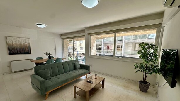 A living room with a sofa, coffee table, and a potted plant. - 2 bedrooms flat near center (Egkomi)