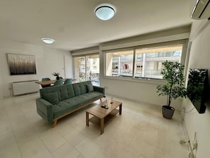 Ein Wohnzimmer mit Sofa, Couchtisch und einer Topfpflanze.