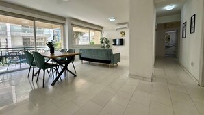 A spacious living area with a sofa, dining table, chairs, and a TV. - 2 bedrooms flat near center (Egkomi)