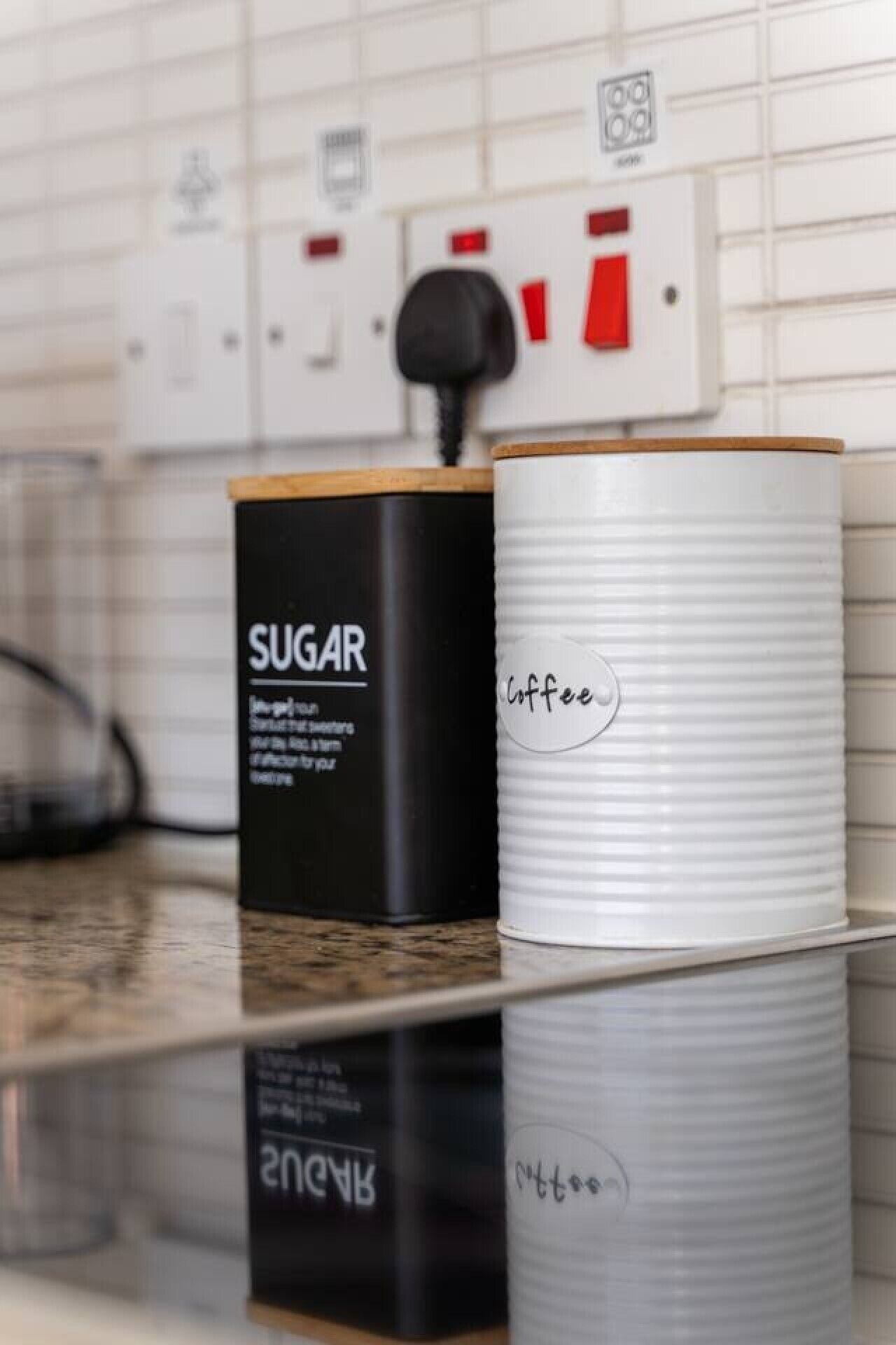 Zwei Behälter mit den Aufschriften 'SUGAR' und 'Kaffee' auf einer Küchenarbeitsplatte.