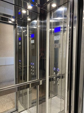 Un ascenseur moderne doté de panneaux en verre et de boutons de commande.