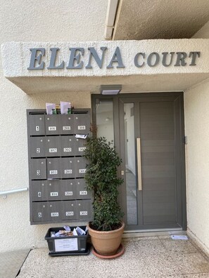 L'entrée d'un immeuble avec une boîte aux lettres et un pot de fleurs.