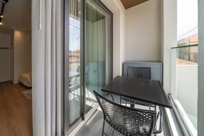 Een balkon met een tafel en stoelen, een schuifpui en uitzicht op de omgeving.