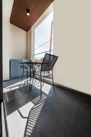 Een balkon met een tafel en stoelen, een uitzicht op de lucht en een gebouw op de achtergrond.