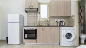 A compact kitchen with a refrigerator, oven, washing machine, and a window above the sink. - Renovated city center studio balcony/terrace view (Nicosia)