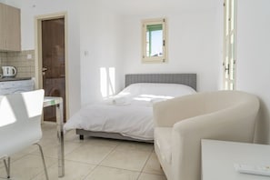Une chambre à coucher avec un lit, une chaise, une table et une fenêtre.