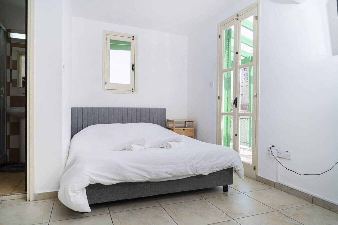 Une chambre à coucher avec un lit, une fenêtre, une porte et une prise de courant.