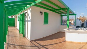 A covered outdoor area with green railings, a white wall, and a tiled floor. - Renovated city center studio balcony/terrace view (Nicosia)