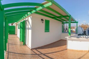 A covered outdoor area with green railings, a white wall, and a tiled floor. - Renovated city center studio balcony/terrace view (Nicosia)