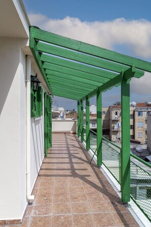 Un balcon agrémenté d’une pergola verdoyante, doté de murs blancs et d’un sol carrelé.