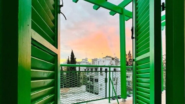 A balcony with a metal railing, a view of the cityscape, and a sunset. - Renovated city center studio balcony/terrace view (Nicosia)