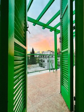 Un balcon avec une balustrade en métal, une vue sur le paysage urbain et un coucher de soleil.