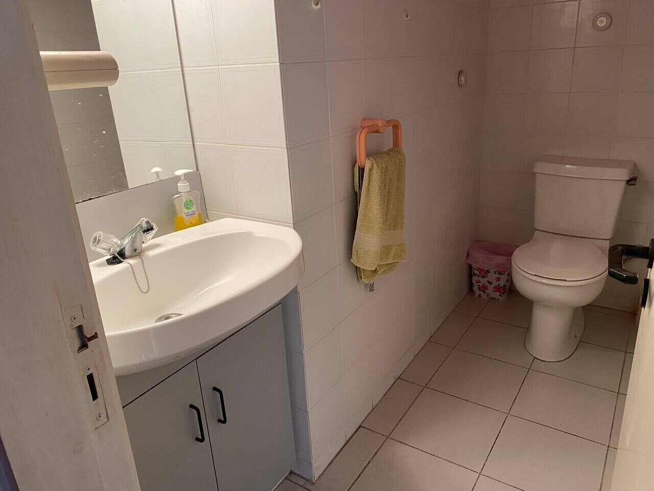 A bathroom with a sink, mirror, toilet, and a towel rack.