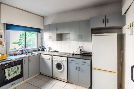 A compact kitchen with a washing machine, dishwasher, and a refrigerator.