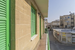 Eine enge Straße mit Gebäuden, die grüne Fensterläden und einen sichtbaren Laden mit der Aufschrift 'ACCESSORIES' zeigen.