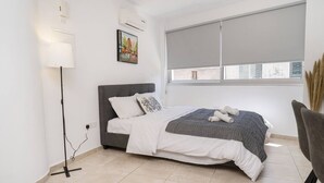 Un dormitorio moderno con una cama, una lámpara de pie, una ventana con persianas y un cuadro en la pared.