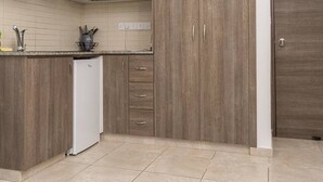 Una cocina con armarios de madera, un refrigerador blanco y piso de baldosas.