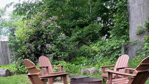 Un cortile con due poltrone Adirondack, un braciere e un recinto in legno.