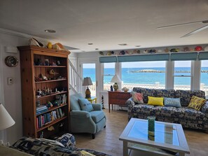 A living room with a bookshelf, a sofa, a coffee table, and a view of the sea. - The Beach House, Crescent Beach, Hull (Hull)