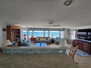 A living room with a view of the ocean, a ceiling fan, and a large TV. - The Beach House, Crescent Beach, Hull (Hull)