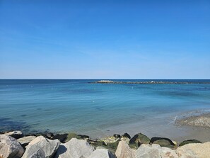 Eine Küstenlandschaft mit klarem, blauem Wasser, einer felsigen Küstenlinie und einer in der Ferne liegenden Felsformation.
