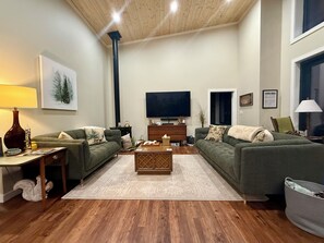 A living room with two sofas, a coffee table, a TV, and a fireplace. - Lodge at Pinhook Gap w/ Sunset Views, Hot tub & EV (Tuckasegee)