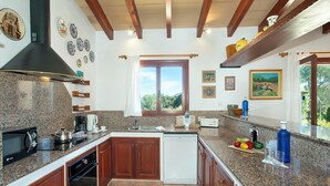 Una cocina con encimeras de granito, armarios de madera, horno empotrado y ventana con vista a la vegetación.