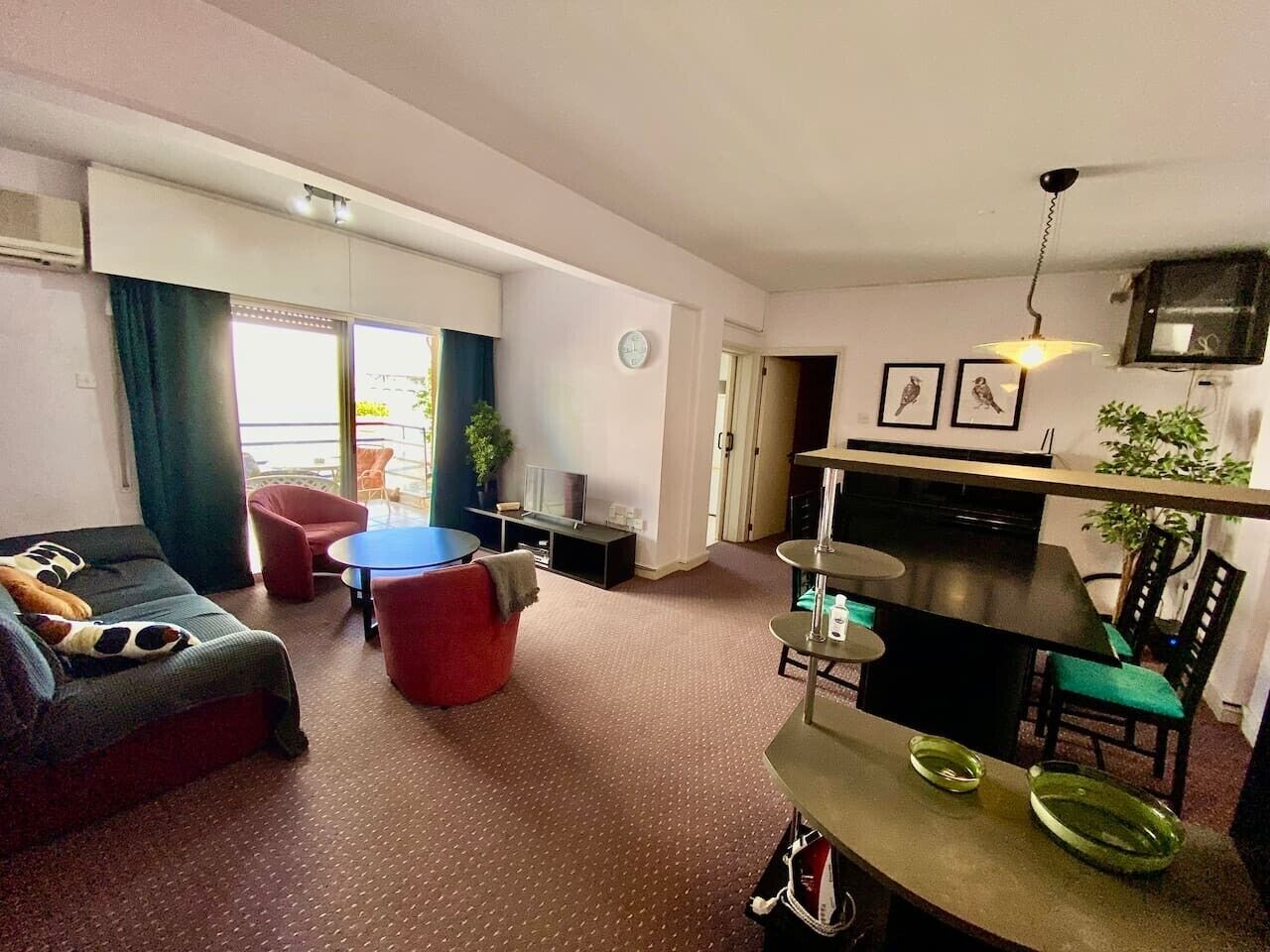 Una sala de estar con un sofá, un sillón rojo y una mesa de comedor con sillas.