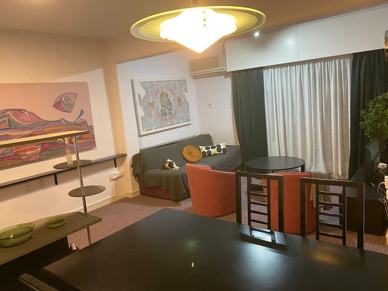 Una sala de estar moderna con comedor, sofá, mesa de centro y un cuadro en la pared.